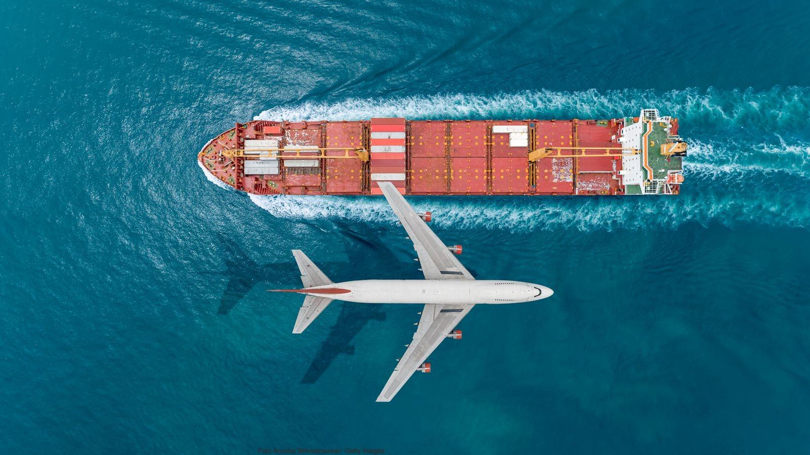 Vista aérea de un avión sobrevolando un buque de carga
